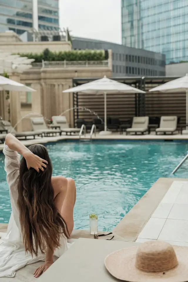 The Ritz-Carlton a Dallas, area piscina con lettini, ombrelloni e una persona seduta